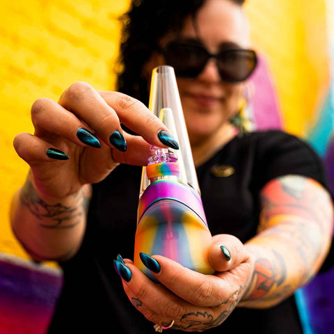 Jae holding a colorful Puffco Rainbow Vape, abstract background